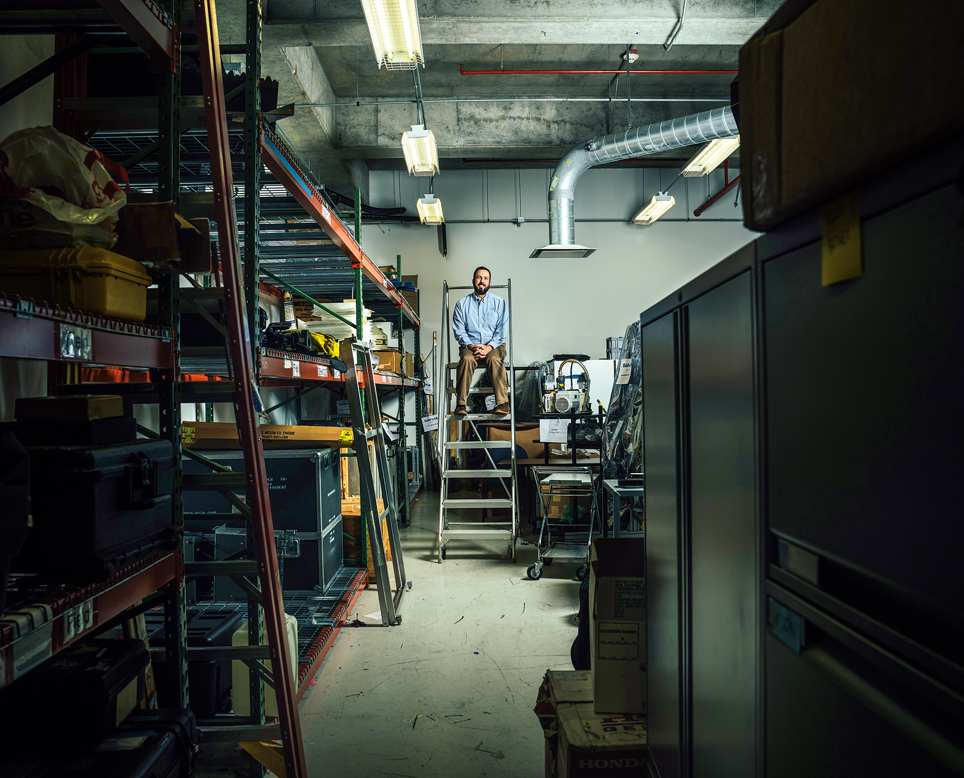 portrait of Noah Petro on a ladder in a storage room